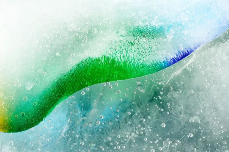 Close-up of green and blue liquids mixing with fine air bubble