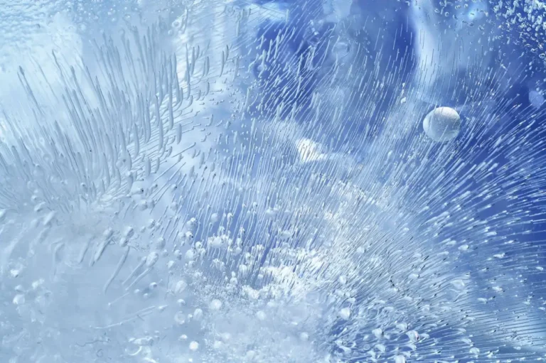 Macro texture of cracked, frozen blue ice with crystalline patterns.